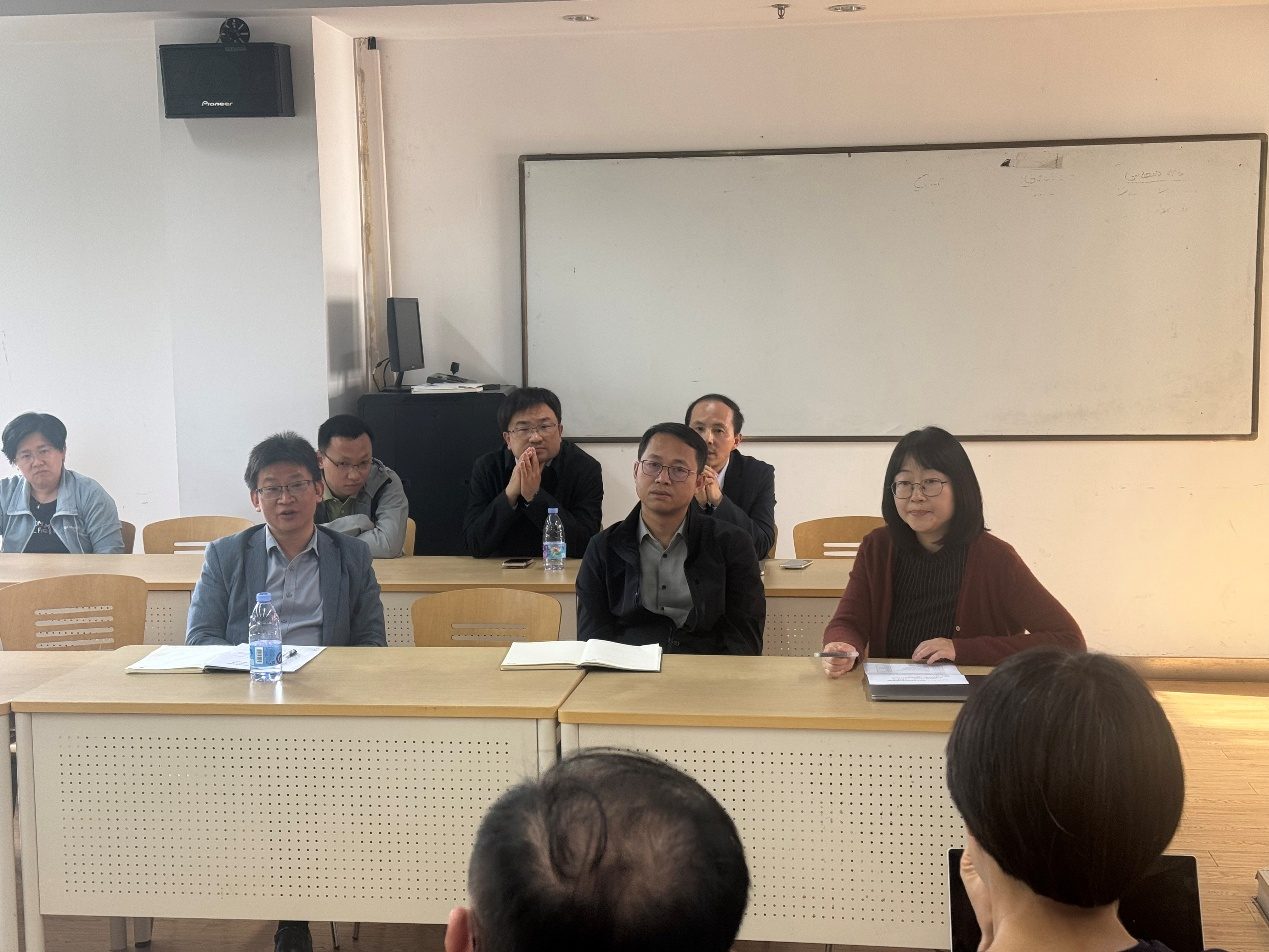三位教师并排坐在长桌一侧交流。